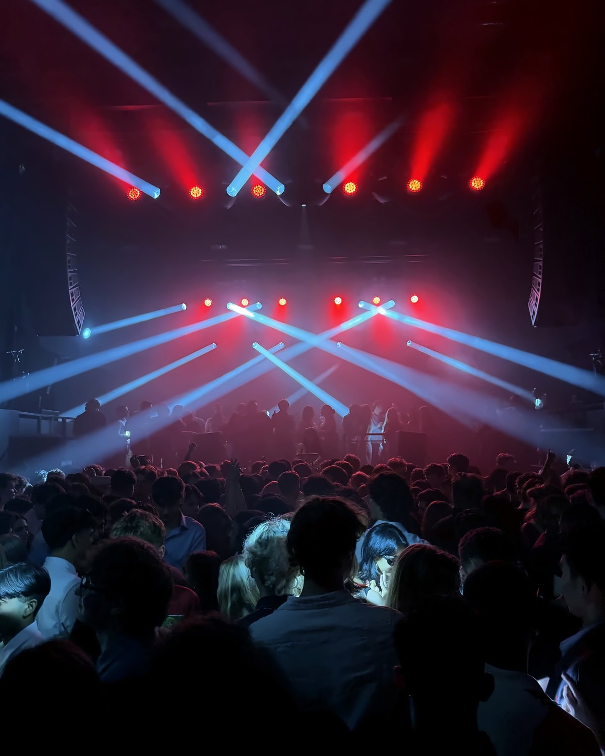 Red and white stage beams over a packed crowd at a Lily Rivers set