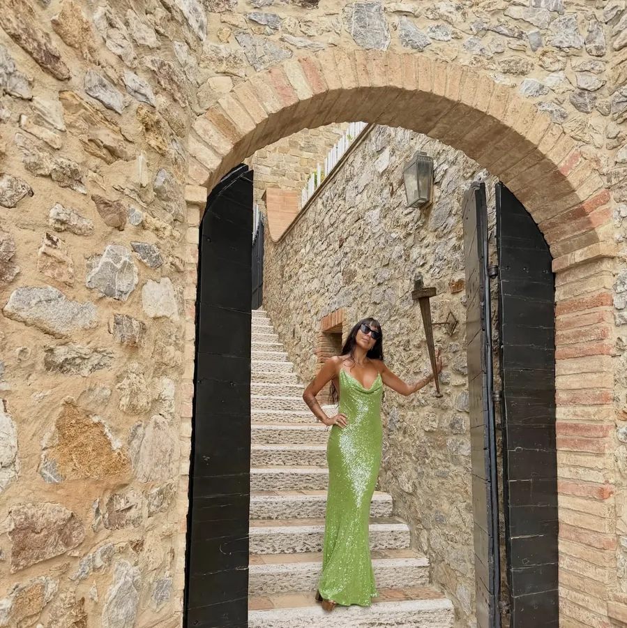 Lily Rivers in a green sequin dress under a stone arch