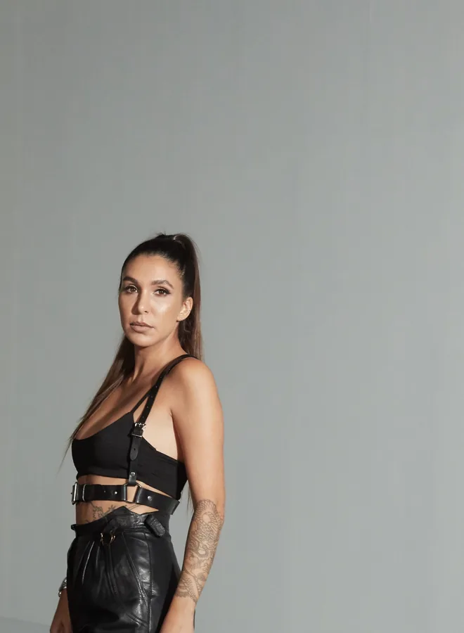 Lily Rivers in black leather against a grey studio backdrop